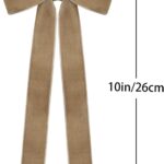 A close-up view of multiple light brown velvet ribbon bows, some hanging on a Christmas tree with soft, blurred lights in the