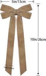 A close-up view of multiple light brown velvet ribbon bows, some hanging on a Christmas tree with soft, blurred lights in the