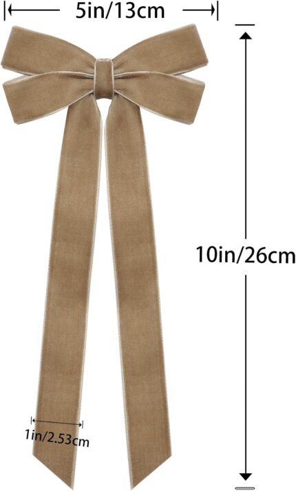 A close-up view of multiple light brown velvet ribbon bows, some hanging on a Christmas tree with soft, blurred lights in the