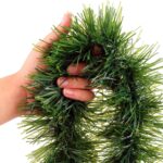 A long, lush green tinsel Christmas garland, non-lit, draped over a mantelpiece with a fireplace below.