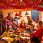 A long, vibrant red tinsel garland twisted and draped over a fireplace mantle with other Christmas decorations.