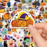 A flat lay of 100 diverse Reaeon Halloween vinyl stickers featuring pumpkins, ghosts, witches, bats, and other spooky designs