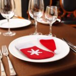 Close-up of red and white non-woven Christmas mini Santa hats and stocking silverware holders on a holiday table.